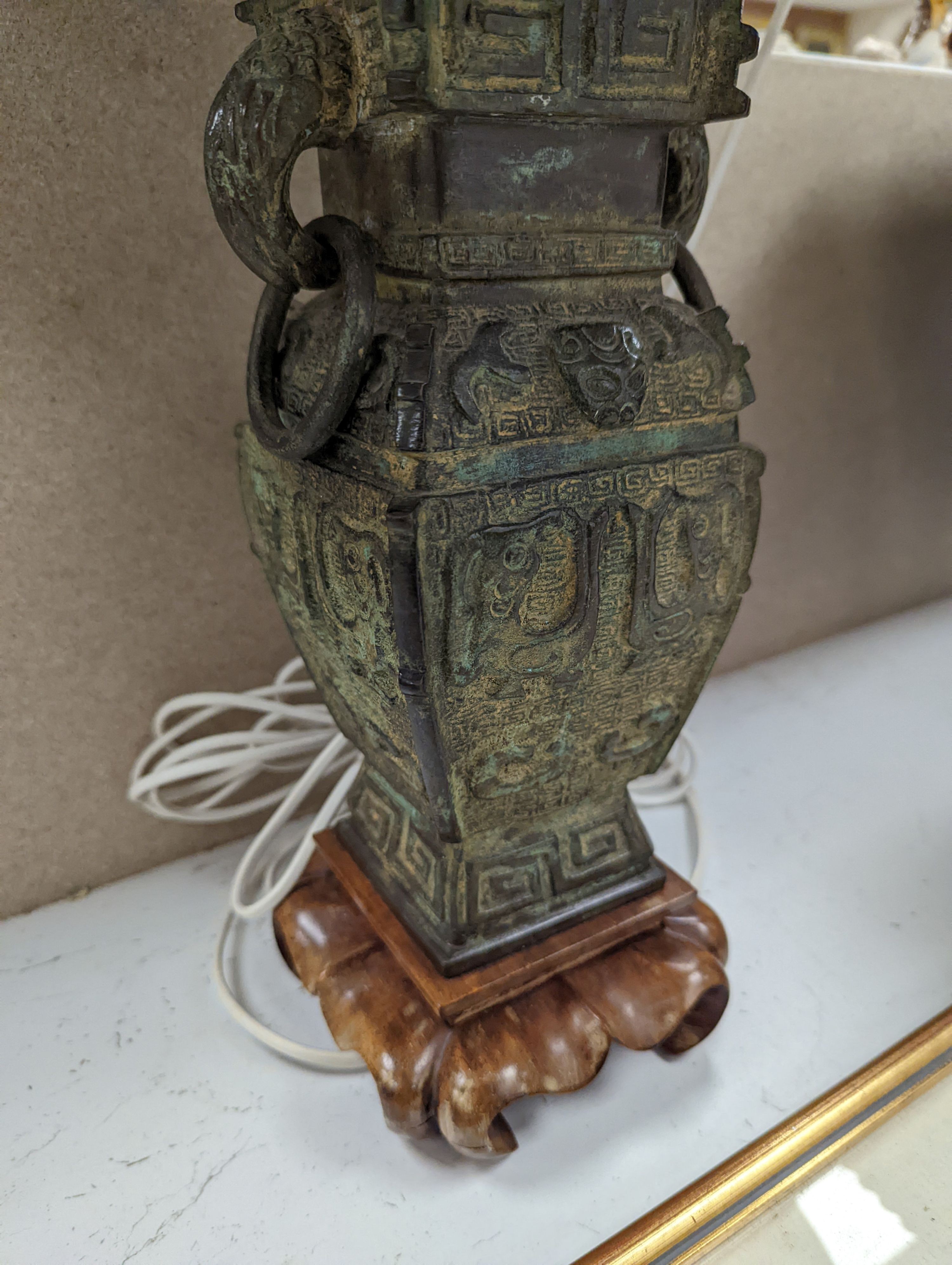 A pair of Chinese archaistic bronze lamps, 37 cms high not including shades or light fitting.